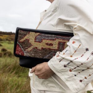 Black leather clutch bag featuring a colourful vintage Turkish rug fragment.