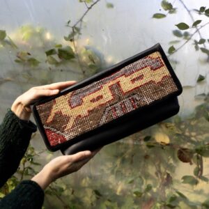 Black leather clutch bag featuring a colourful vintage Turkish rug fragment.
