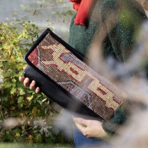 Black leather clutch bag featuring a vintage Turkish rug.